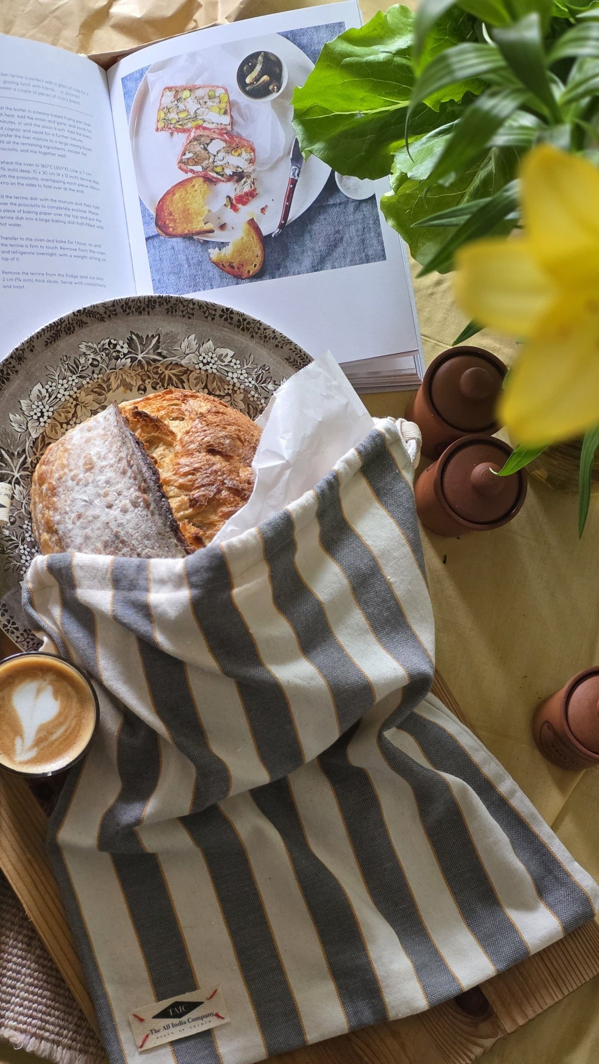 Striped towel on a table with bread, coffee, and a book