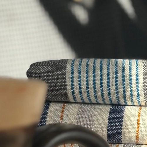 Stack of folded striped fabric on a chair with blurred background