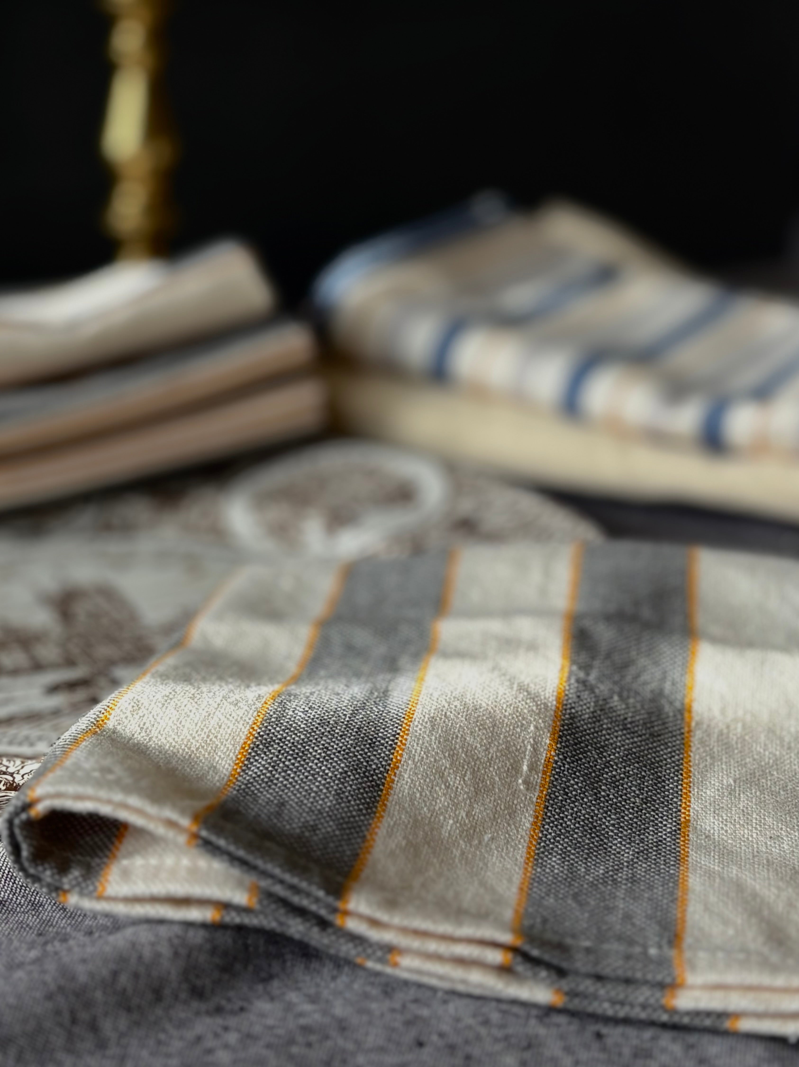 Folded fabric with gray and gold stripes on a dark background