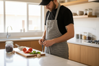 Man in a kitchen preparing food on a cutting board with various ingredients.