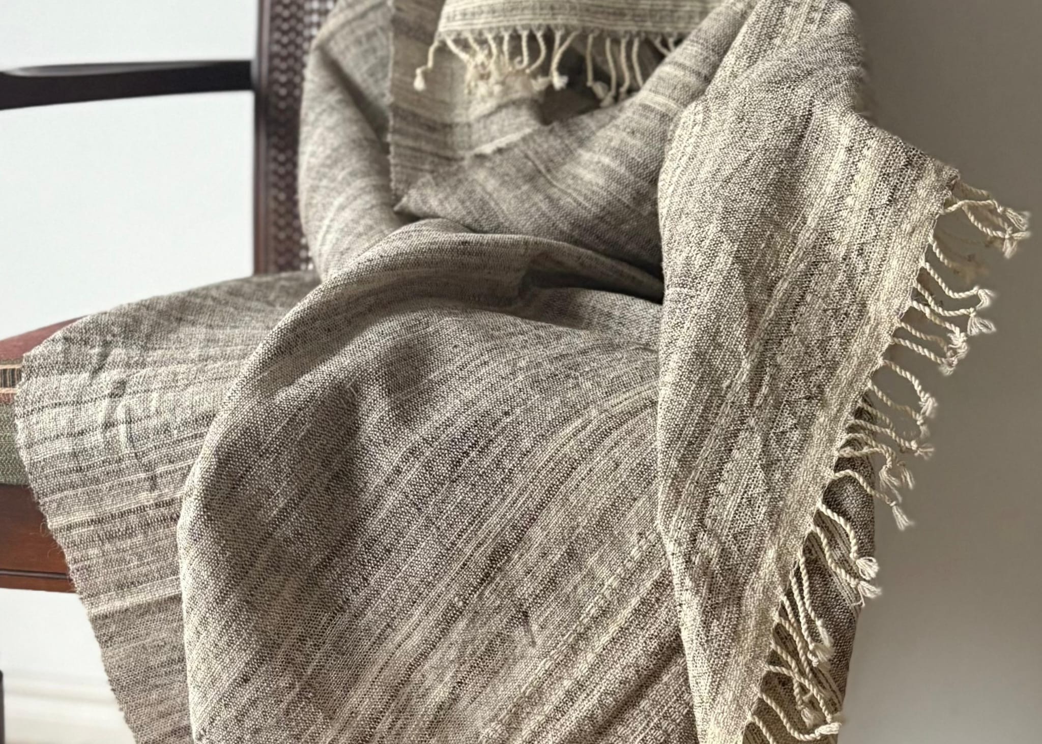 Textured blanket draped over a chair with a neutral background
