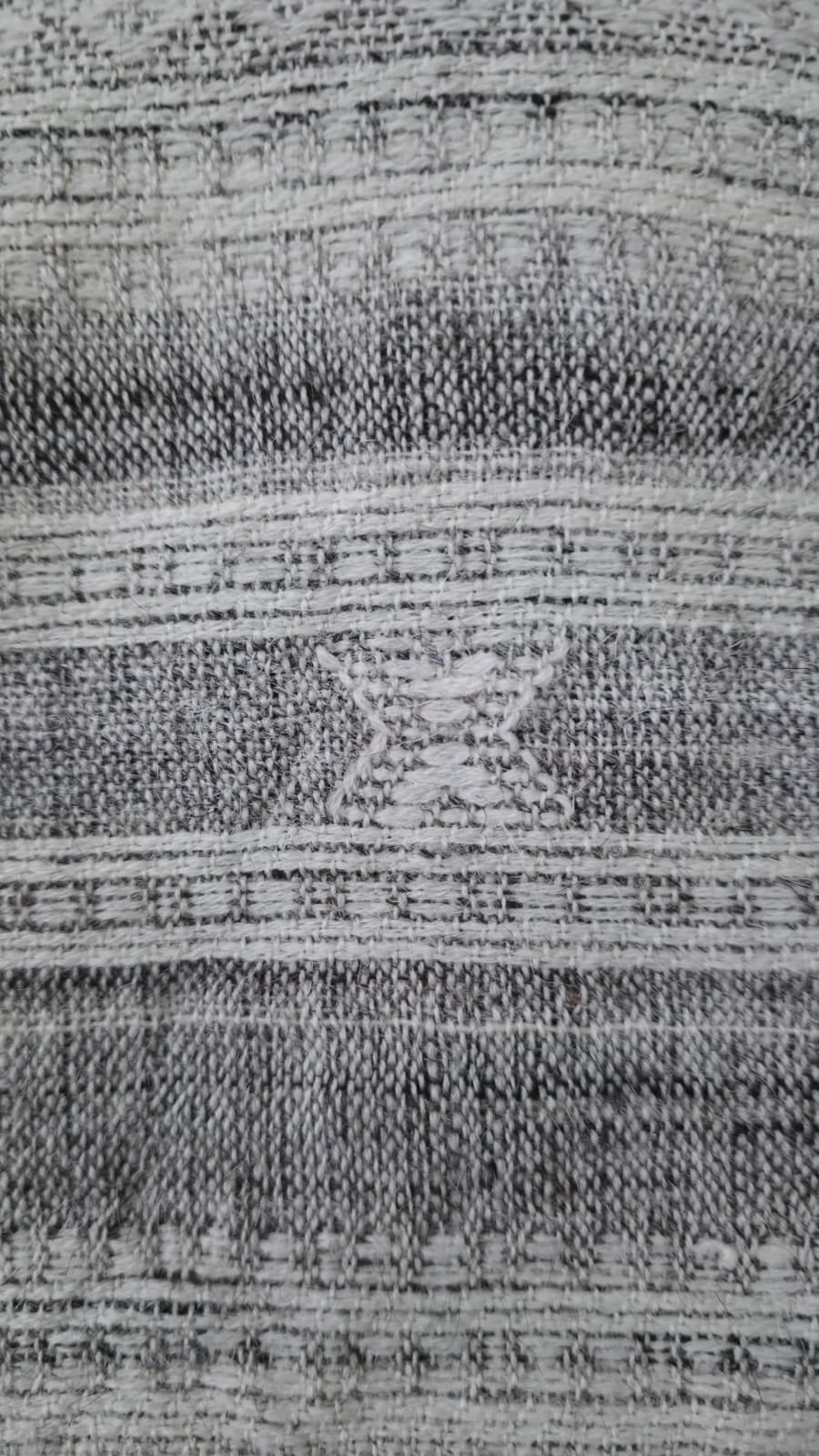 Close-up of a textured gray and black rug with geometric pattern