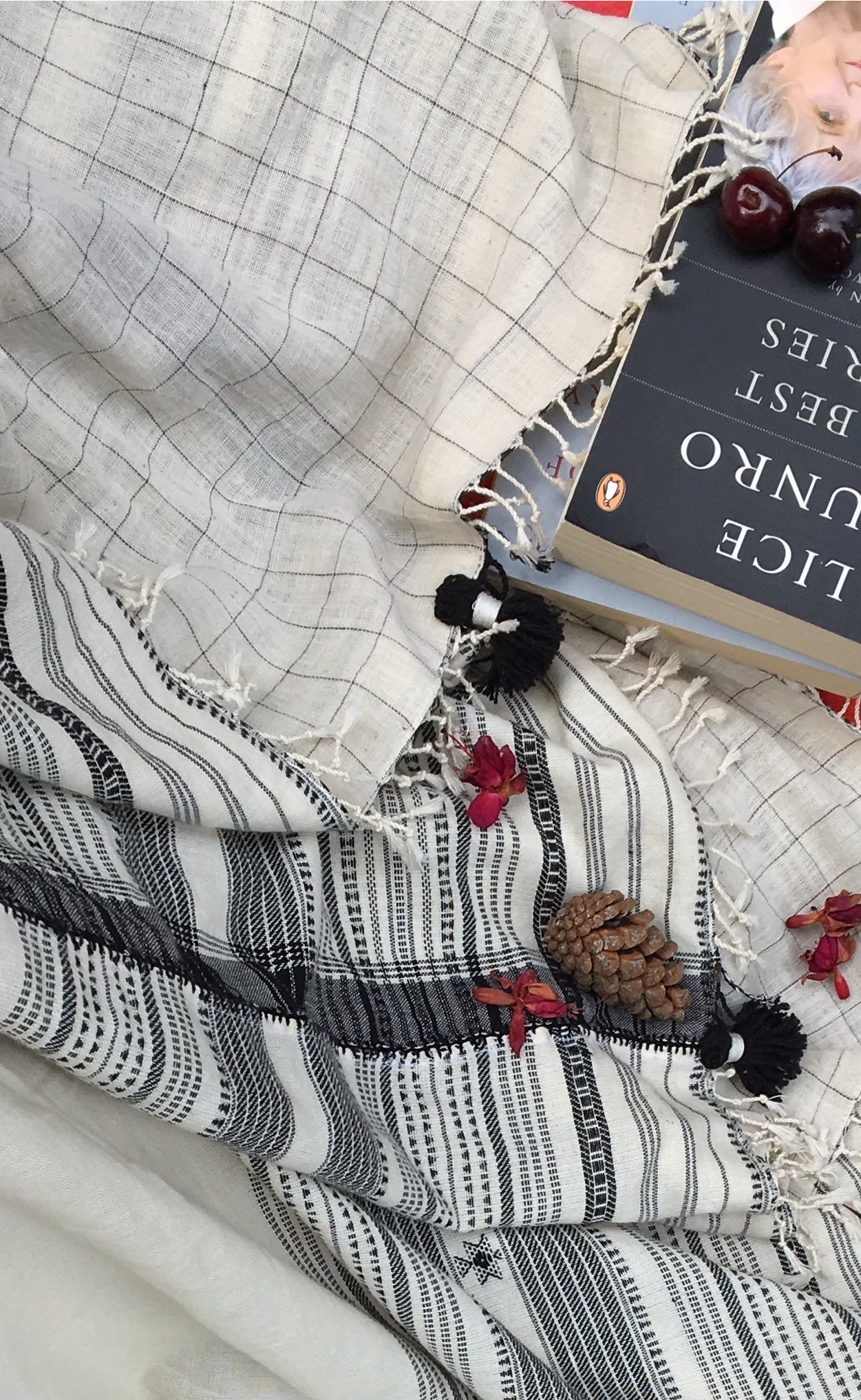 Textile with black and white pattern on a surface with books and flowers.