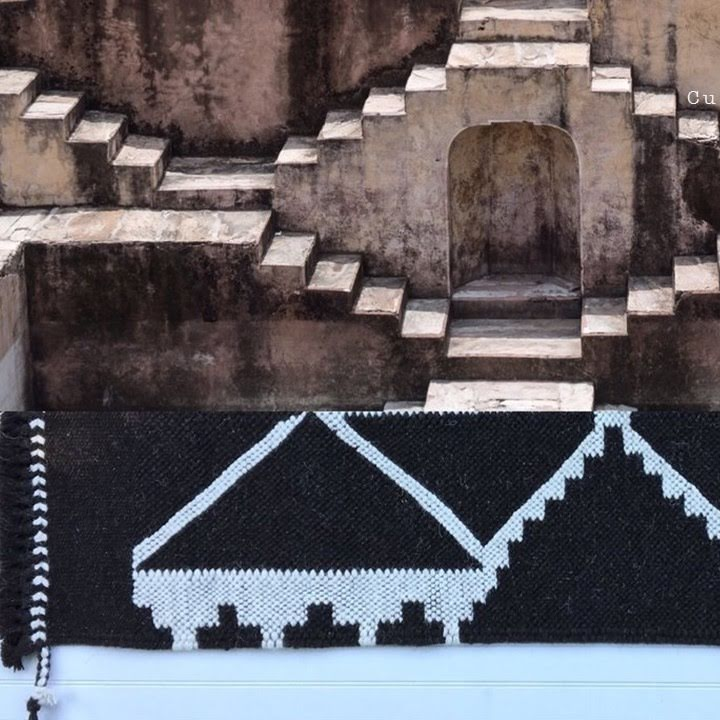 Black and white patterned rug with geometric design in front of stone steps.